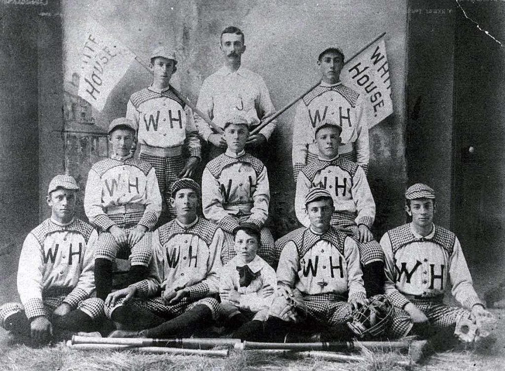 Antique photo of nine baseball players, one coach and a mascot.