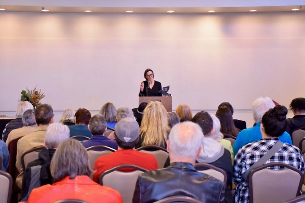 Friday Gretchen speaking in front of a room full of people.