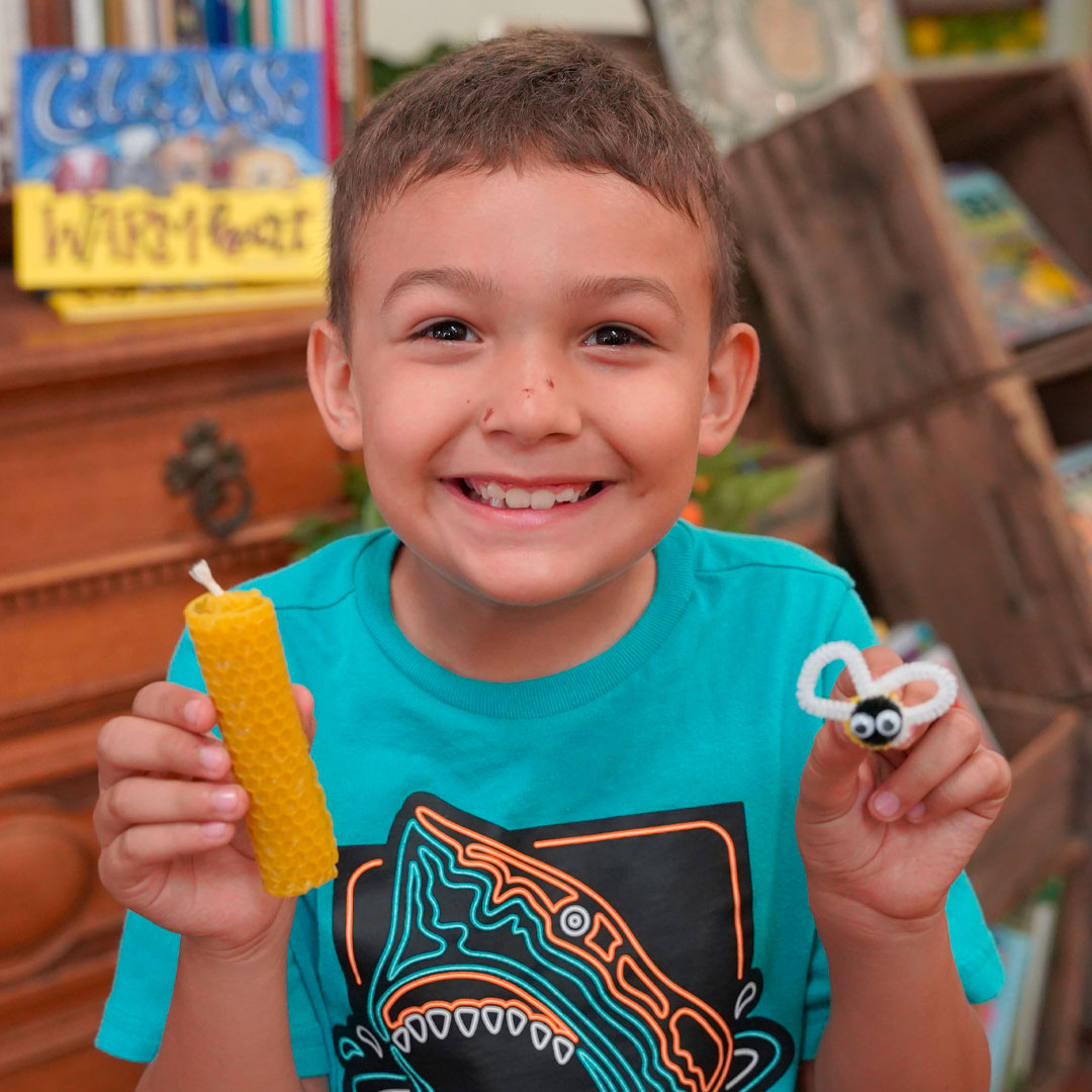 Photo of smiling child holding a honey comb candle